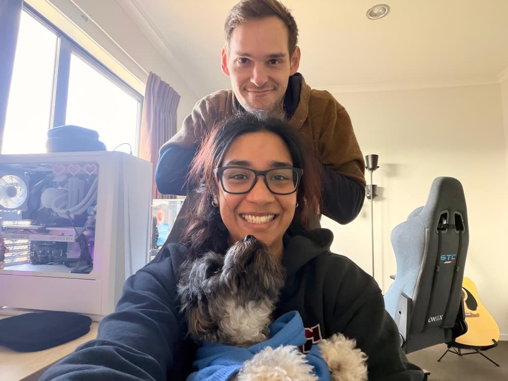 Rein and Revathy at the desk at home, with one of the dogs in her arms